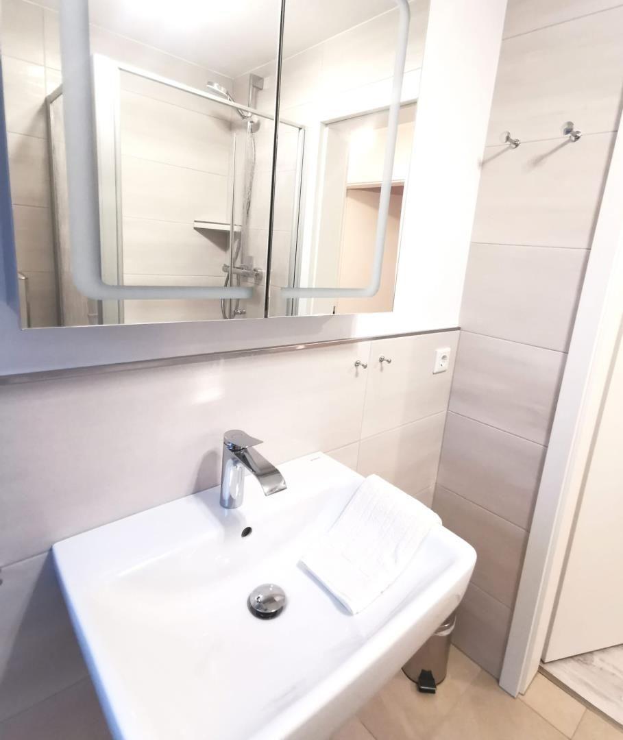 Badezimmer mit Waschbecken, Spiegel und Dusche.