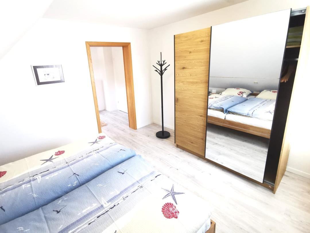 Schlafzimmer mit Doppelbett, Spiegelschrank und Kleiderständer.