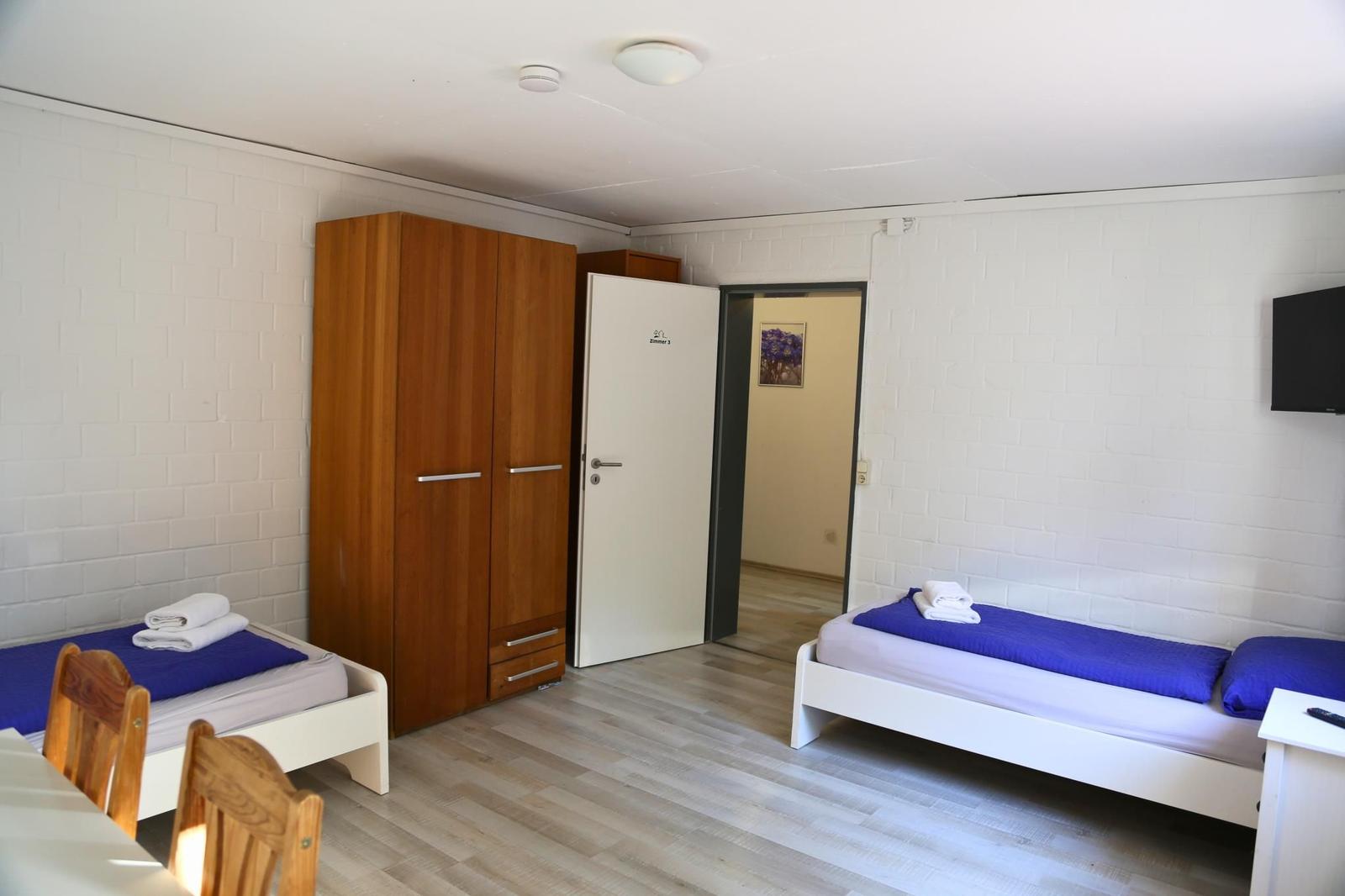 Zimmer mit zwei Betten, Schrank und Fernseher an der Wand.