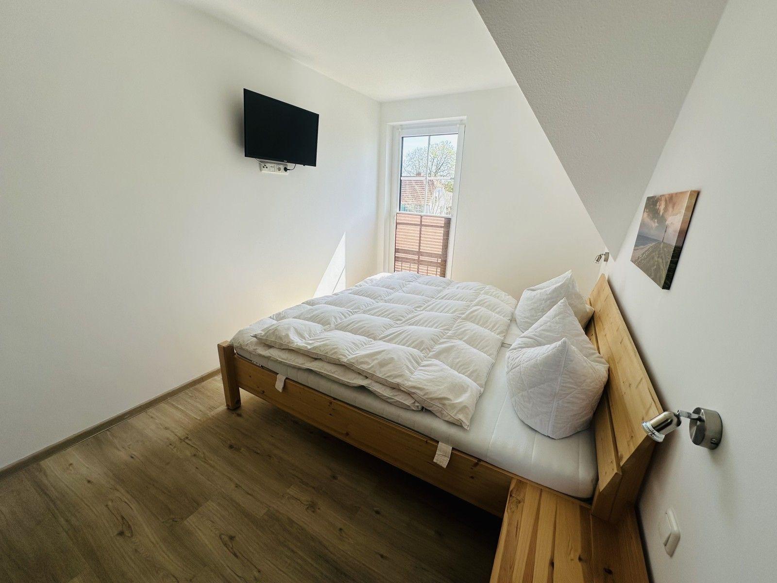Schlafzimmer mit Bett, Fenster und Wand-TV