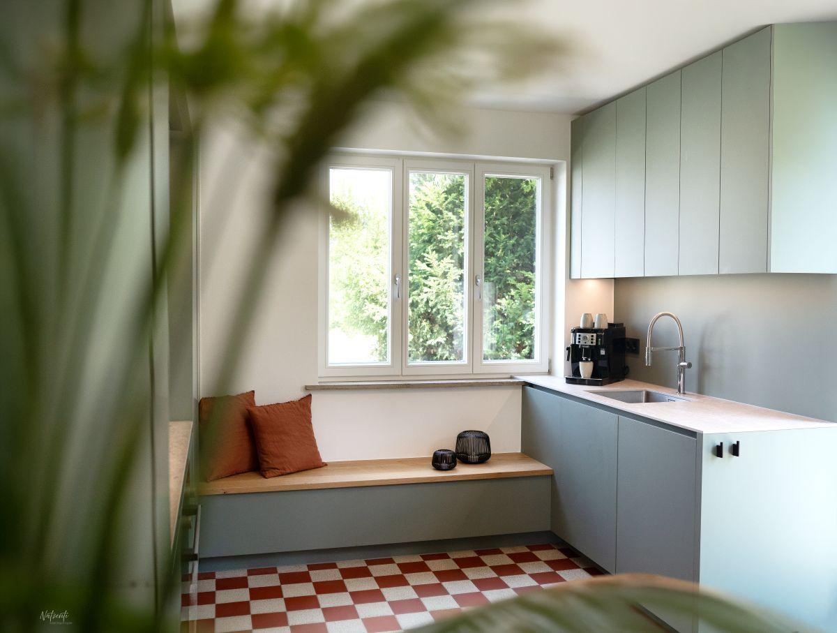 Küche mit Sitzbank unter Fenster, Kaffeemaschine und Spüle.