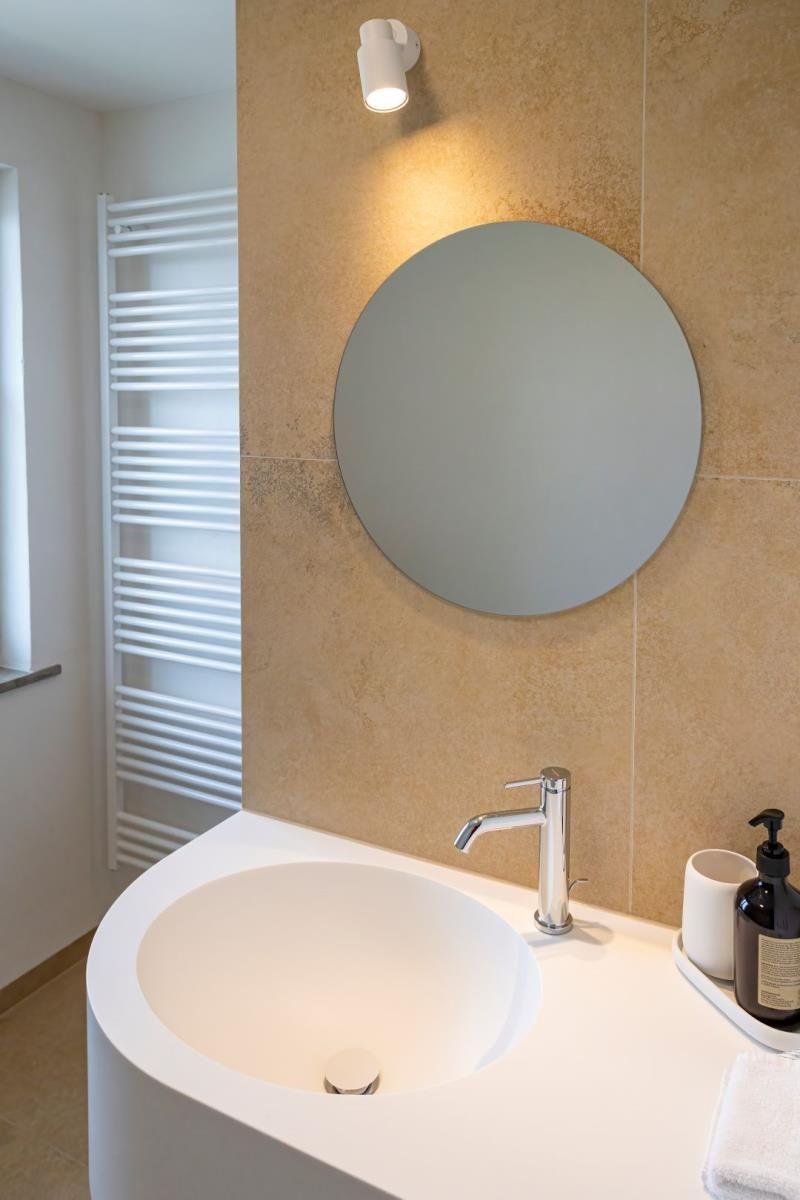 Waschbecken mit Spiegel und Duschbereich im Badezimmer.