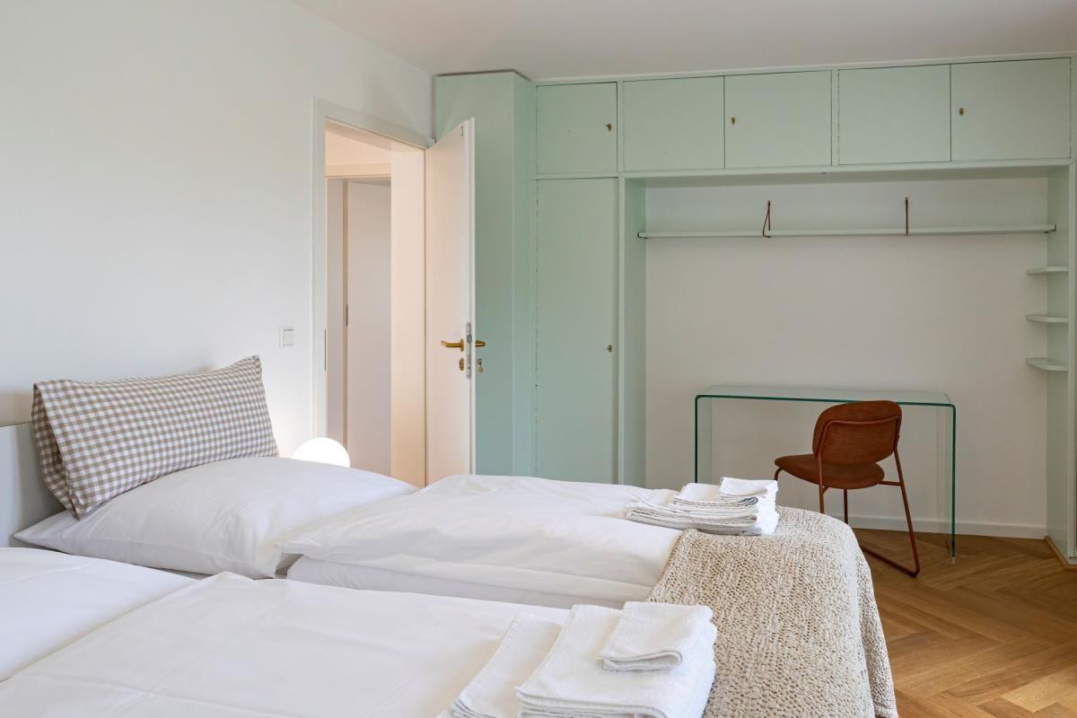 Zwei Betten, Kleiderschrank und Schreibtisch mit Stuhl im Zimmer.