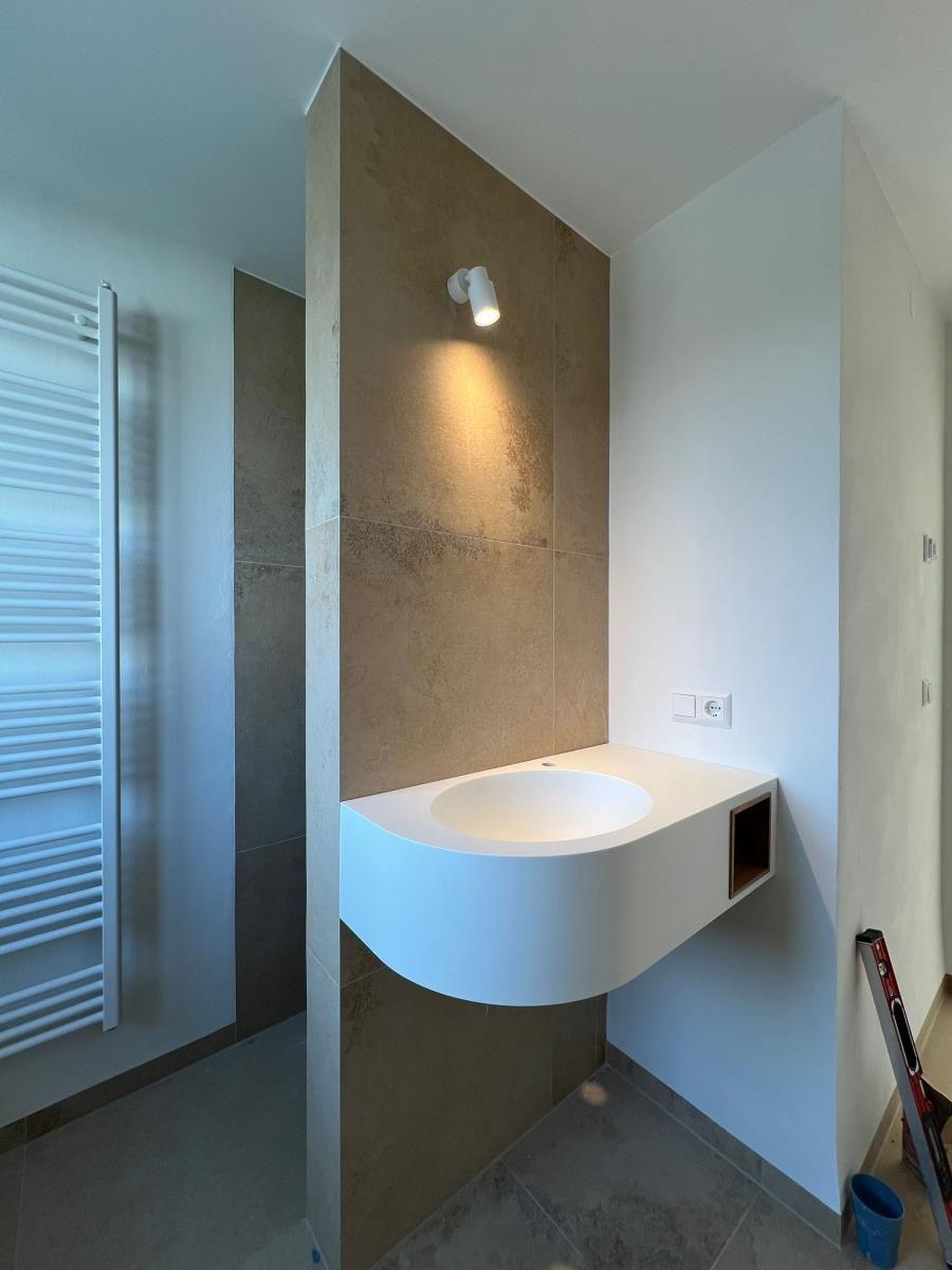 Badezimmer mit Waschbecken, Wandheizung und Beleuchtung.
