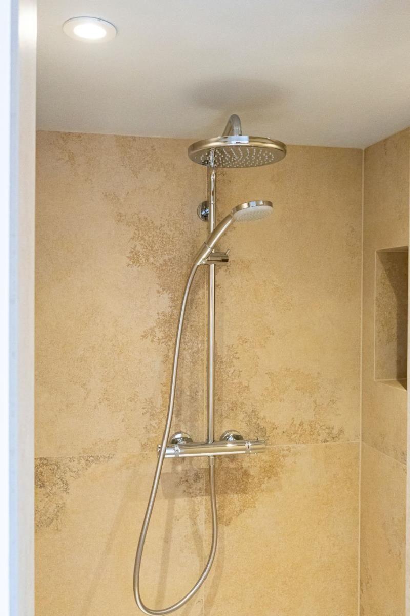 Dusche mit Duschbrause und Handbrause an der Wand