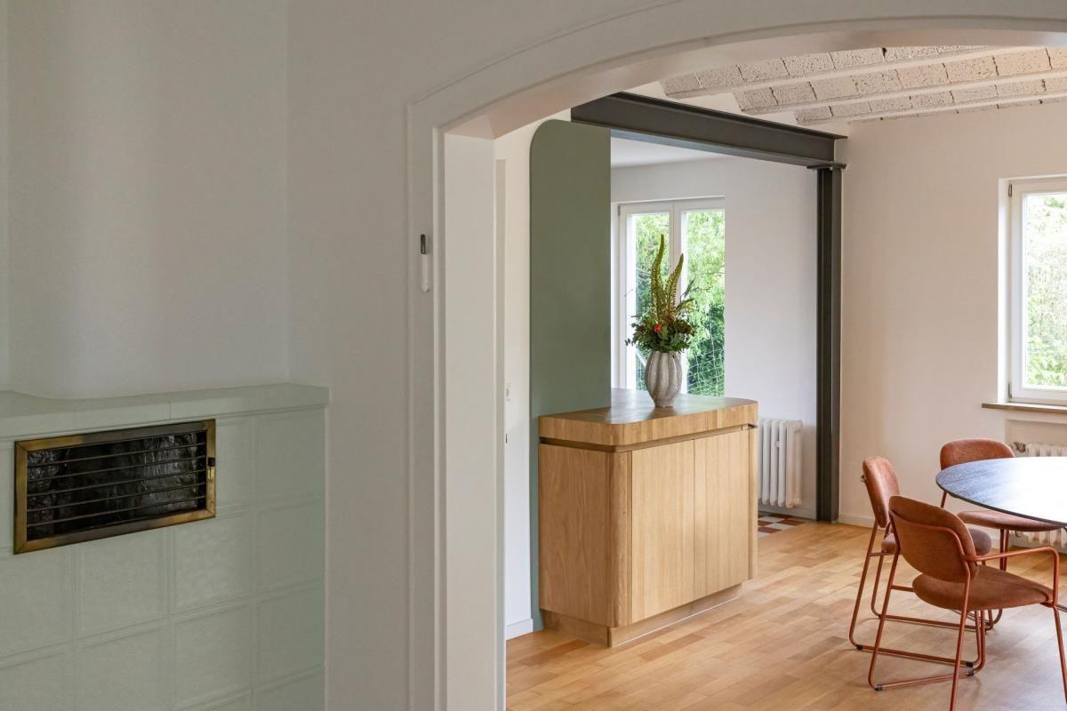 Eingangsbereich mit Holzschrank und Blick in Esszimmer mit Tisch und Stühlen.