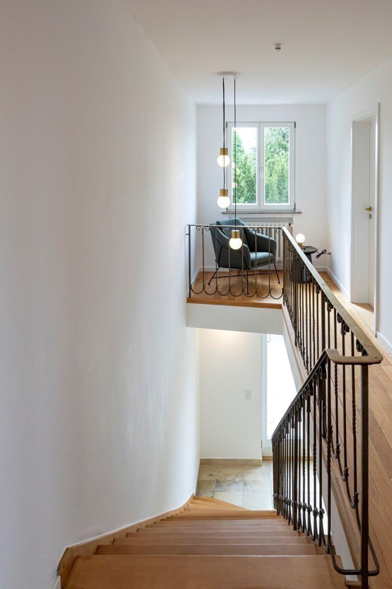 Holzstufen führen zu einer Galerie mit Sitzgelegenheit und Fensterblick.