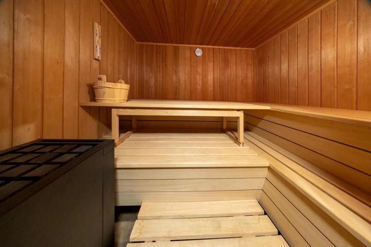Sauna mit Holzbank und Steintisch. Holzwände und -boden. Holzschale auf der Bank.