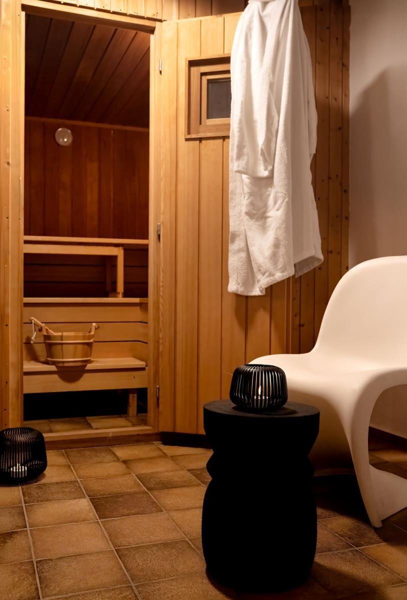 Sauna mit Holzwand, Sitzbank, Eimer und Bademantel an der Tür.