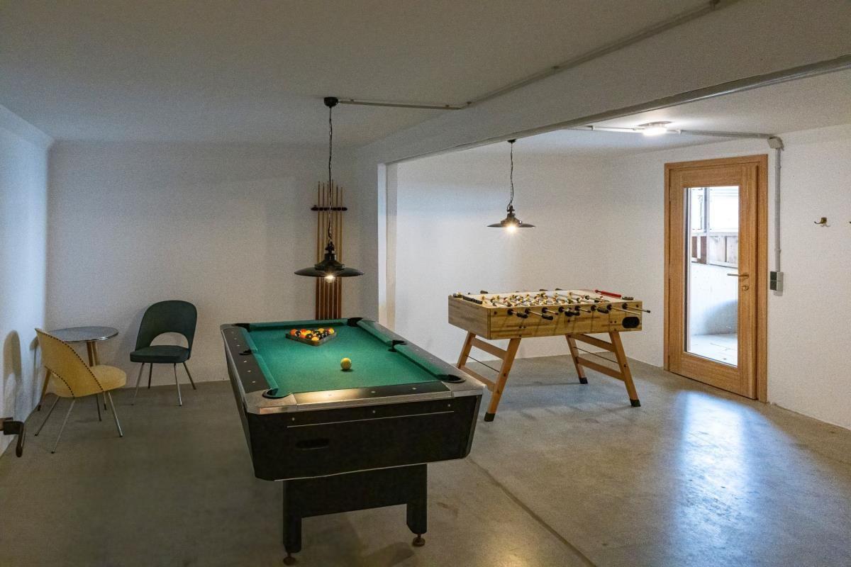 Raum mit Billardtisch und Tischfußball, zwei Hängelampen und eine Tür.