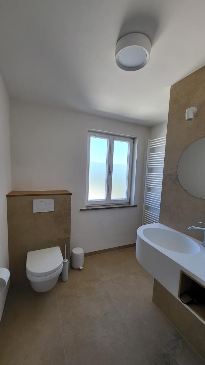 Badezimmer mit Toilette, Waschbecken und Fenster