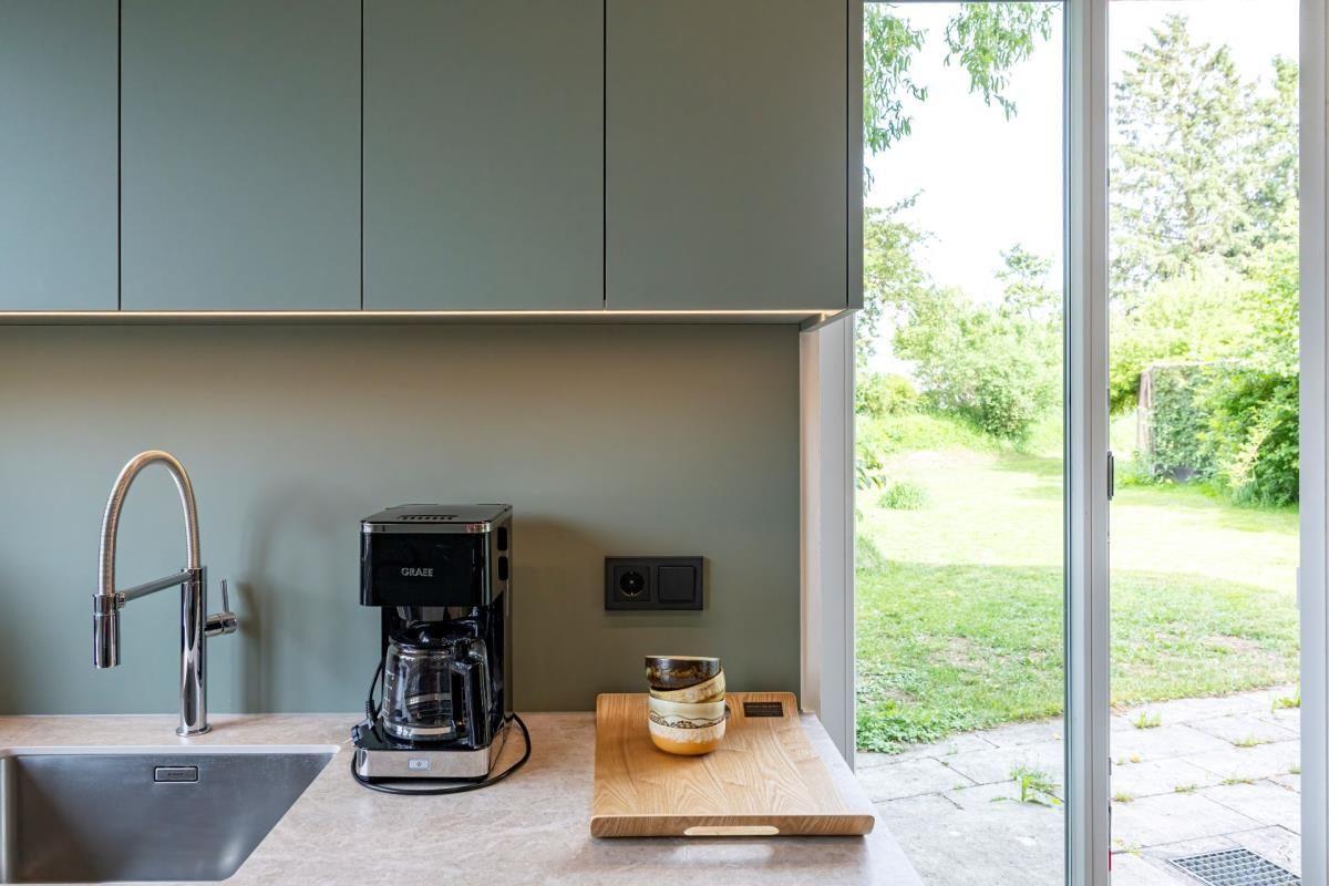 Küche mit Spüle, Kaffeemaschine und Blick auf den Garten