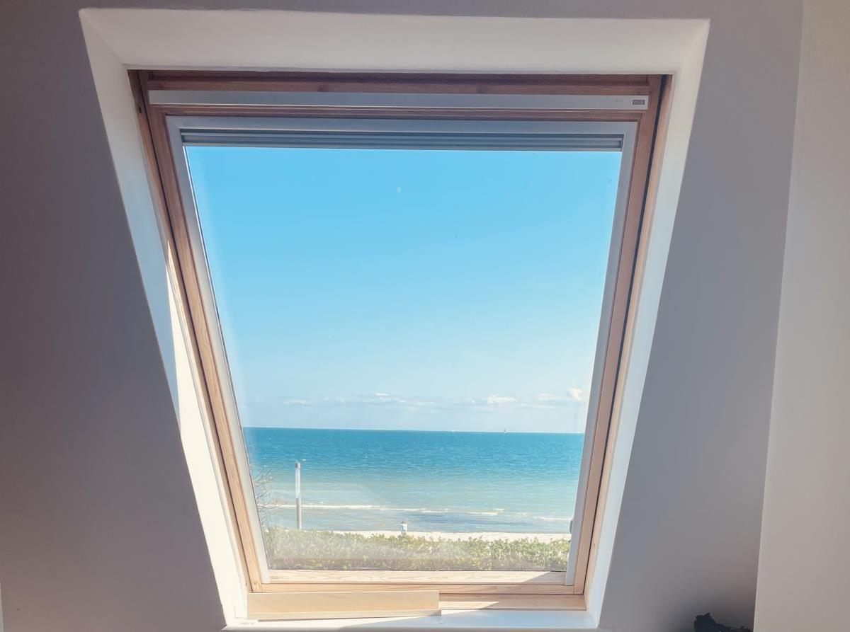 Dachfenster mit Blick auf das Meer und Strand