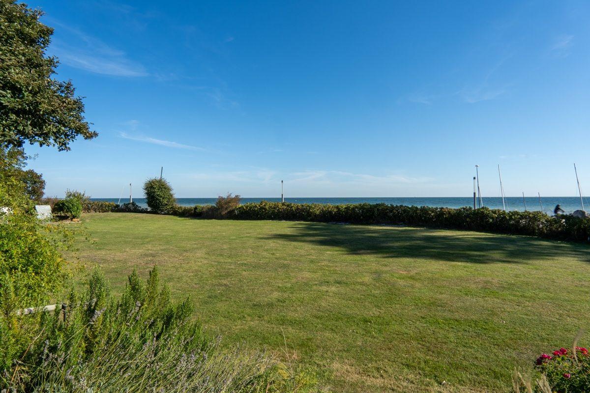 Grüner Rasenbereich mit Blick auf das Meer und Segelboote.