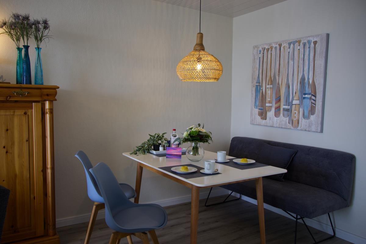 Esszimmer mit Tisch, Stühlen und Wandbild mit Ruderern.