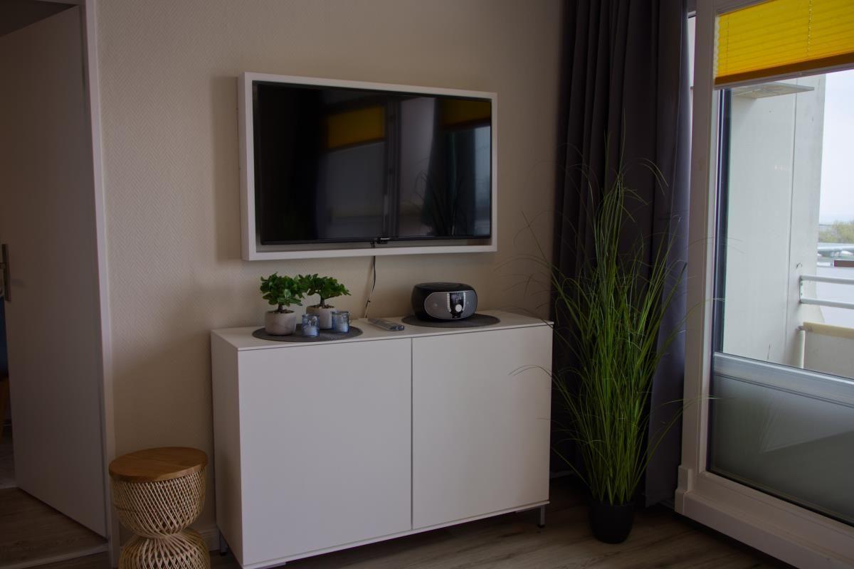 Wandmontierte TV, weißer Sideboard, Pflanzen und Fenster mit Blick.
