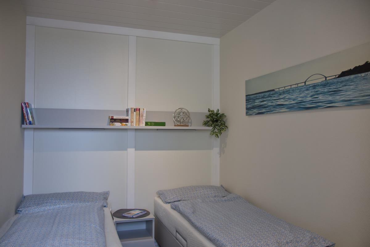 Zwei Einzelbetten, Schrank mit Regal und Wandbild mit Brücke.