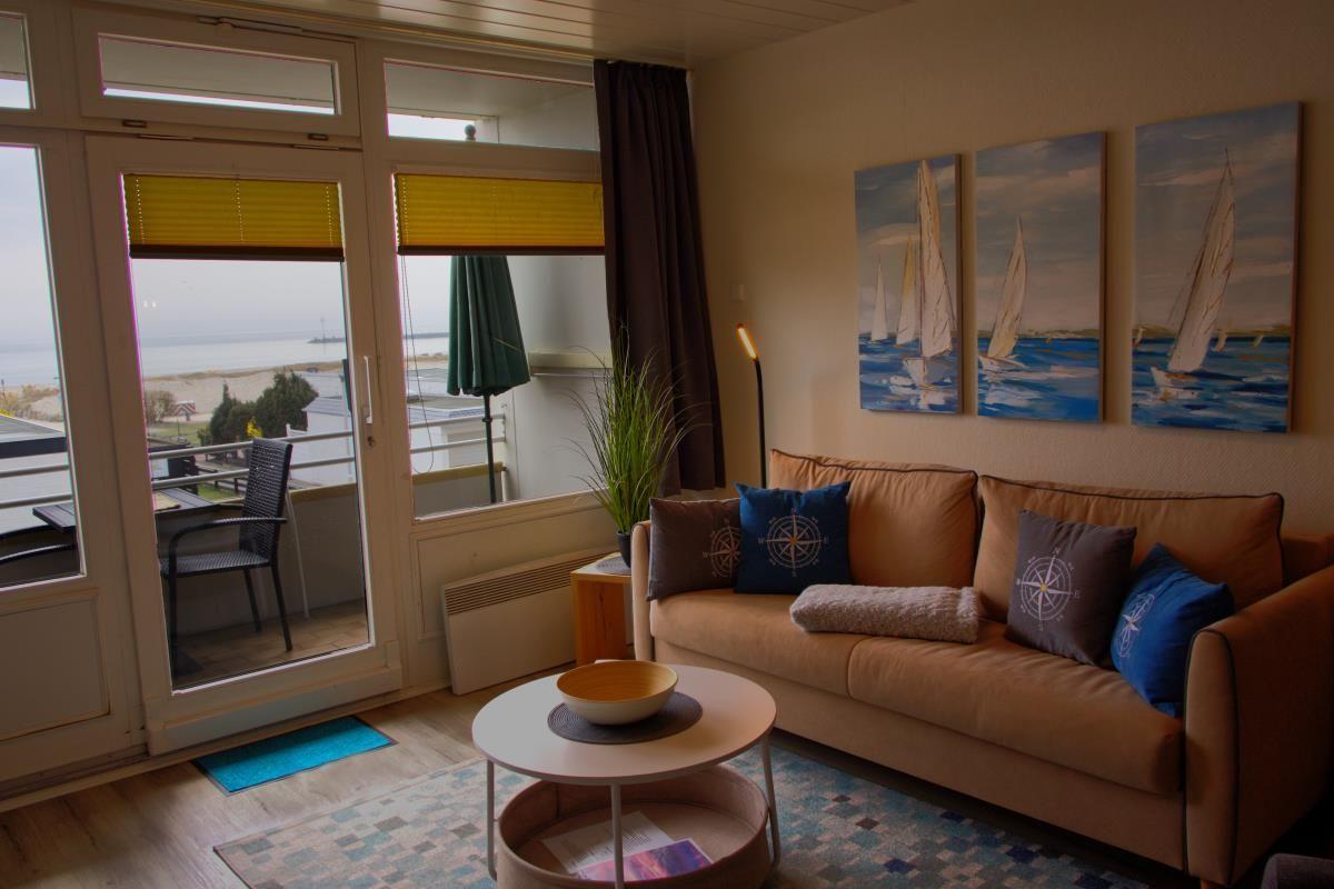 Wohnzimmer mit Sofa, Tisch und Blick auf die Küste.