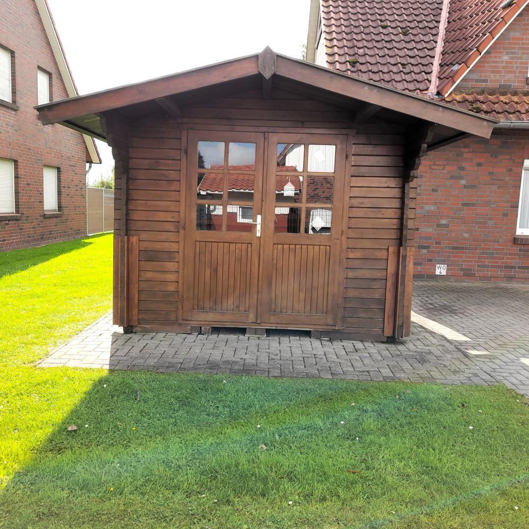 Wooden garage with double doors and glass windows on paved ground.