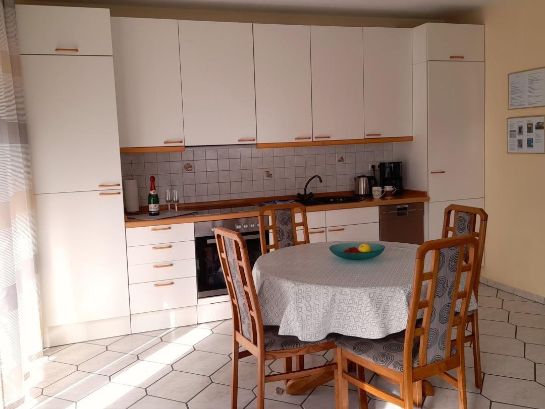 Kitchen with dining area, white cabinets, round table, and wooden chairs.