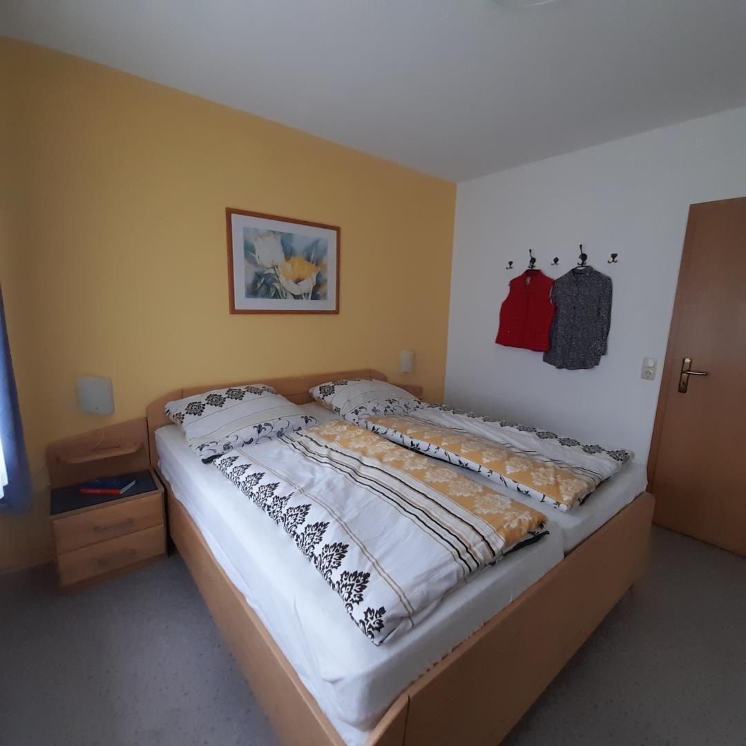 Bedroom with double bed, nightstand, and wall picture.