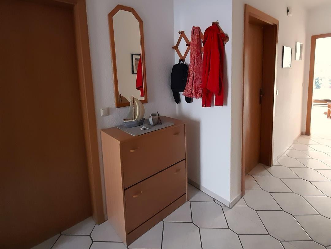 Entryway with cabinet, mirror, and coat hooks on the wall.