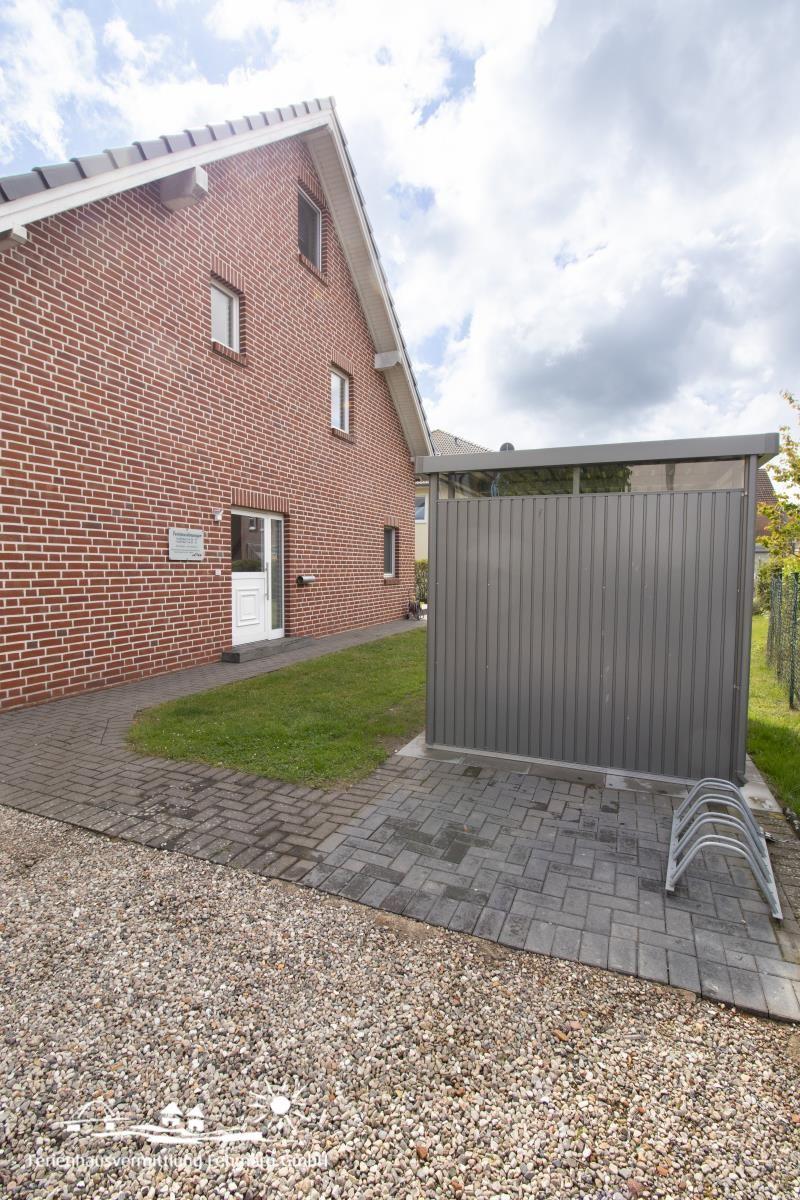 Zwei-geschossiges Haus mit Garten, Garagenabdeckung und Kiesbereich.