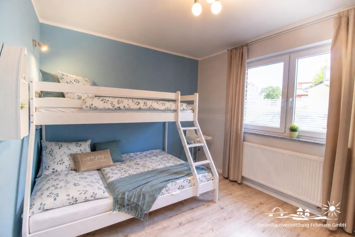 Zimmer mit Doppelstockbett, Fenster und Holzboden.