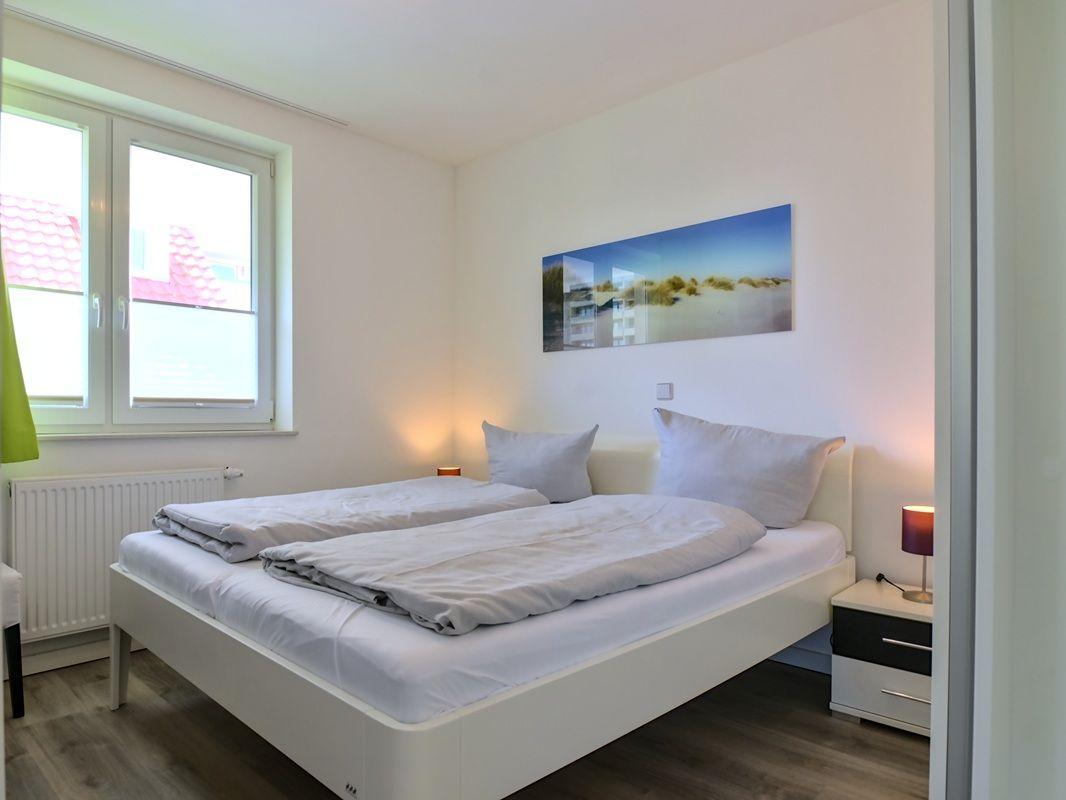 Schlafzimmer mit Doppelbett, Fenster und Wandbild.