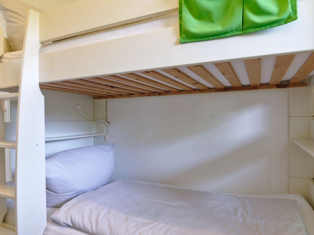 Obere und untere Schlafstelle im Doppelstockbett mit grüner Decke.