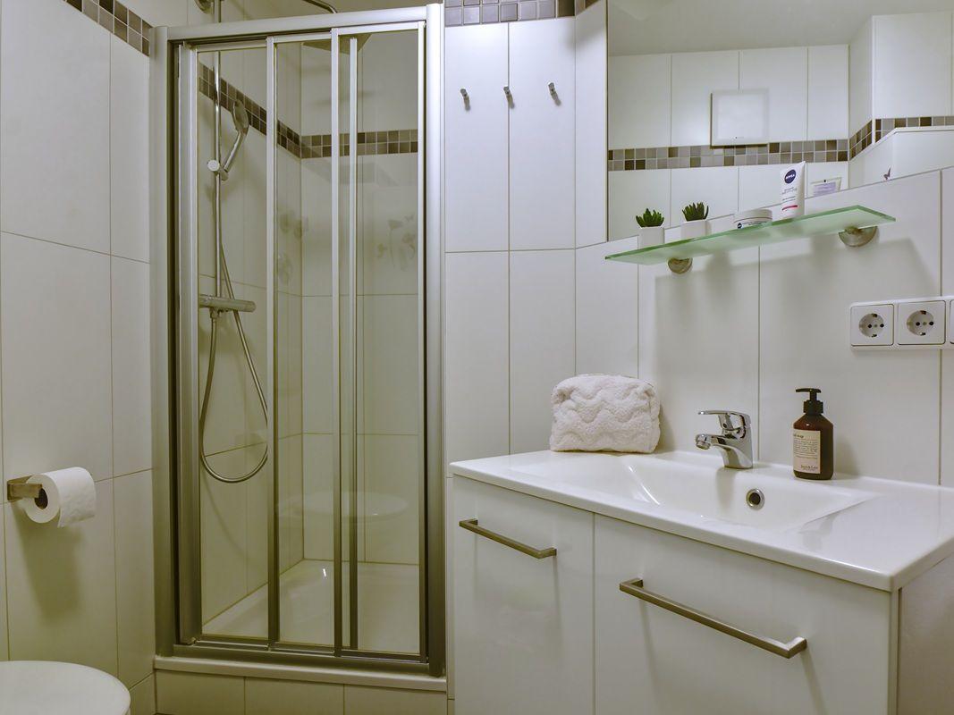 Badezimmer mit Dusche, Waschbecken und Spiegelschrank.