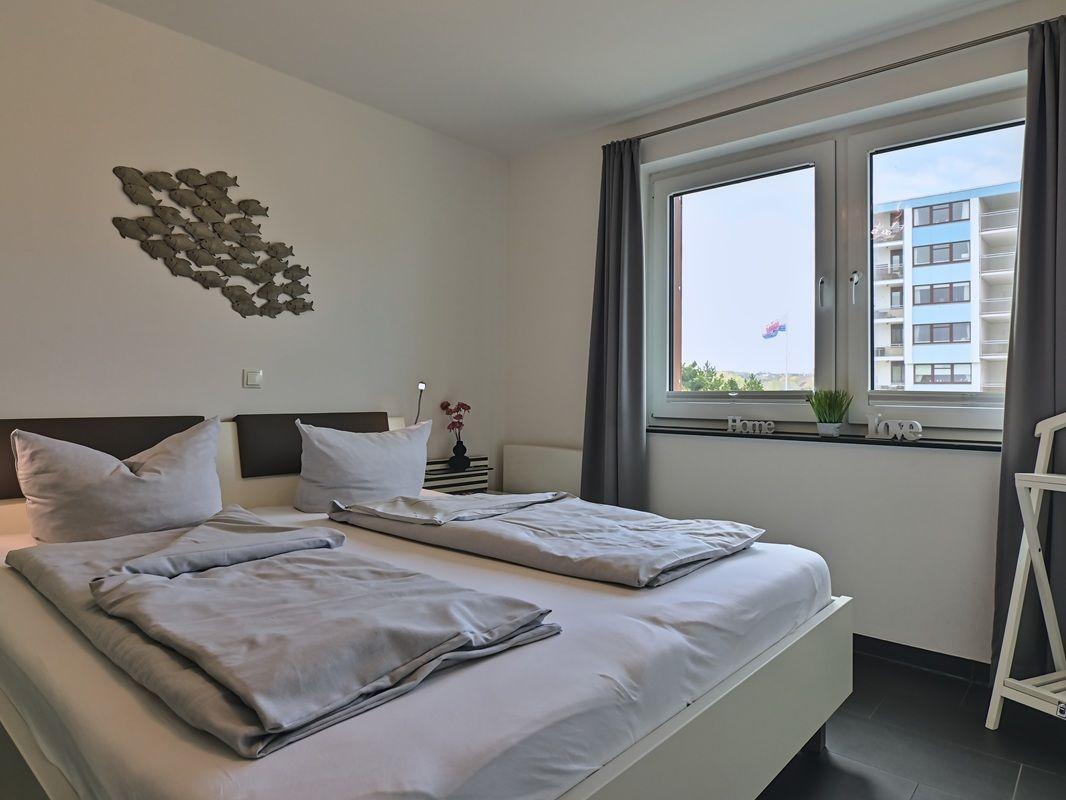 Zimmer mit Doppelbett, Fenster und Wanddekoration