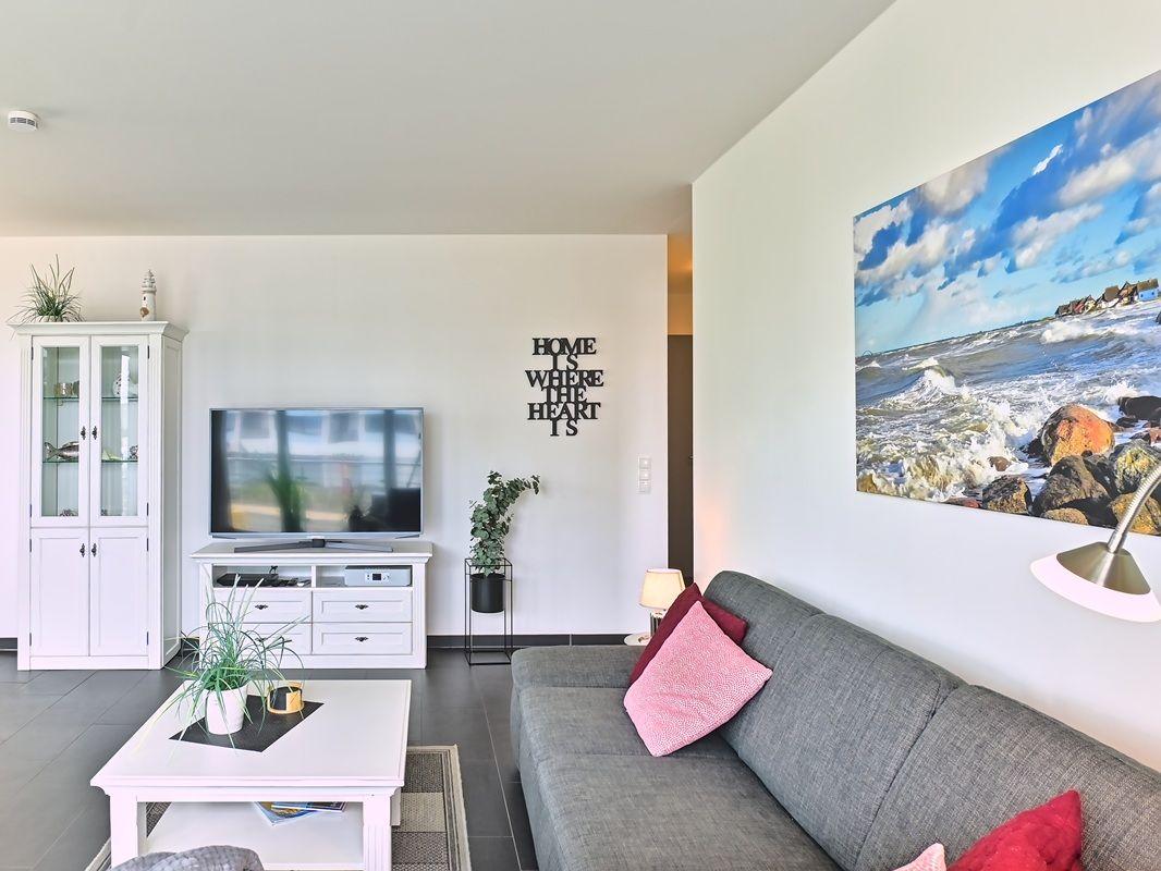 Wohnzimmer mit Sofa, Fernseher und Wandbild an der Wand.