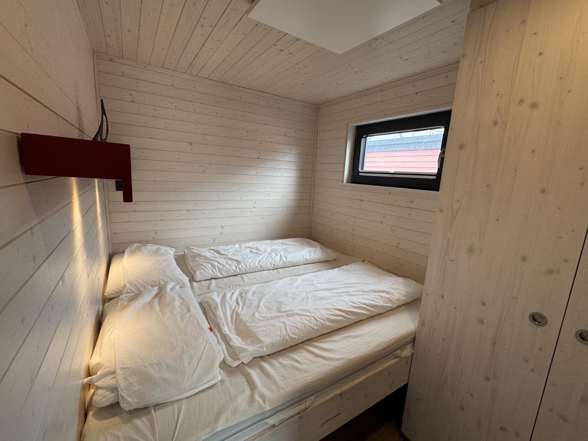 Schlafzimmer mit Doppelbett, Holzwand und Fenster