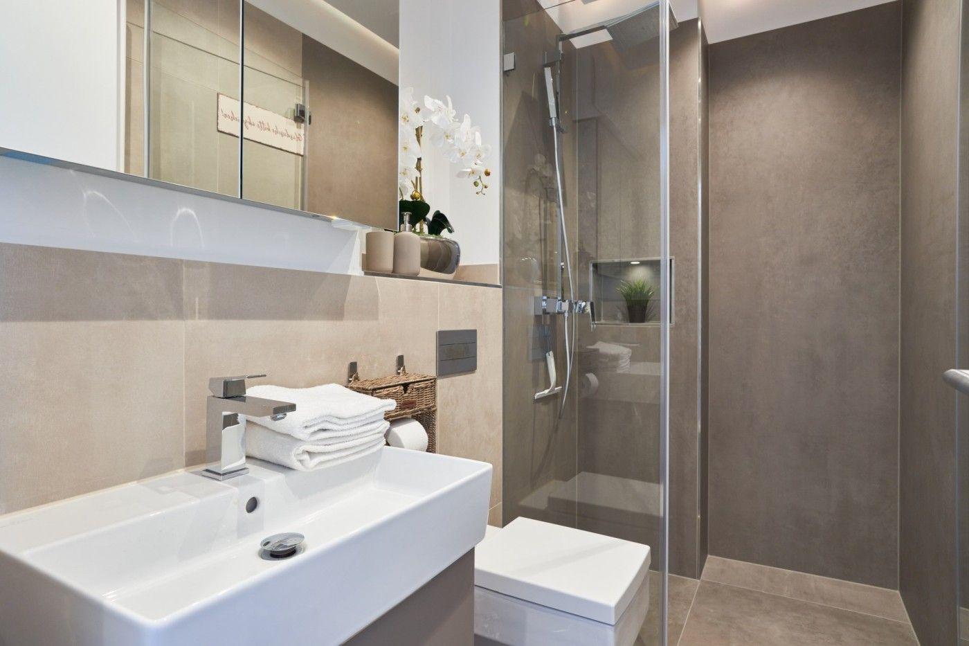 Badezimmer mit Dusche, Waschbecken und Toilette. Moderne Einrichtung mit Spiegel und Blumen.