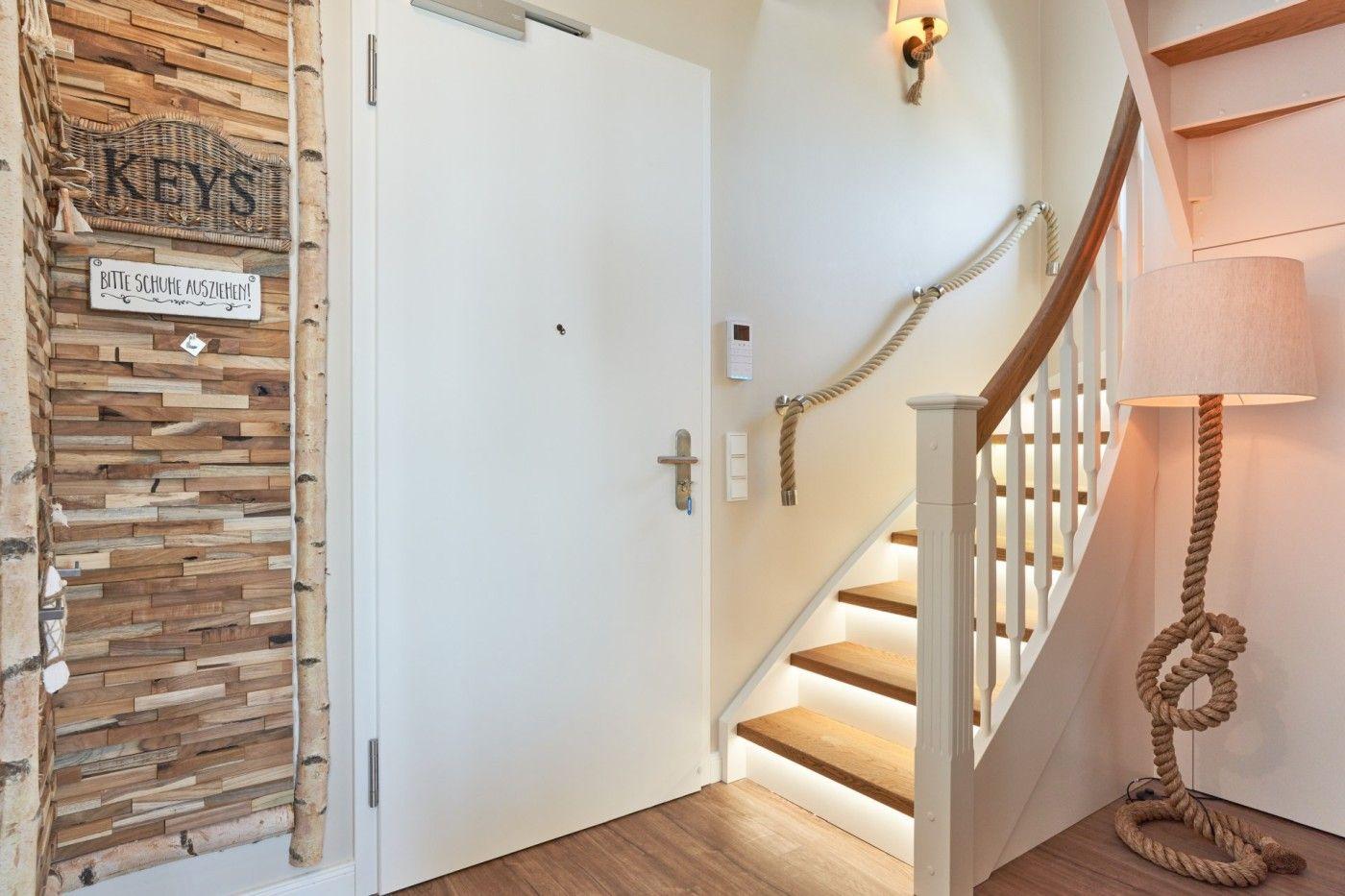 Eingangsbereich mit Holzwand, Tür und Treppe mit Seilgeländer.