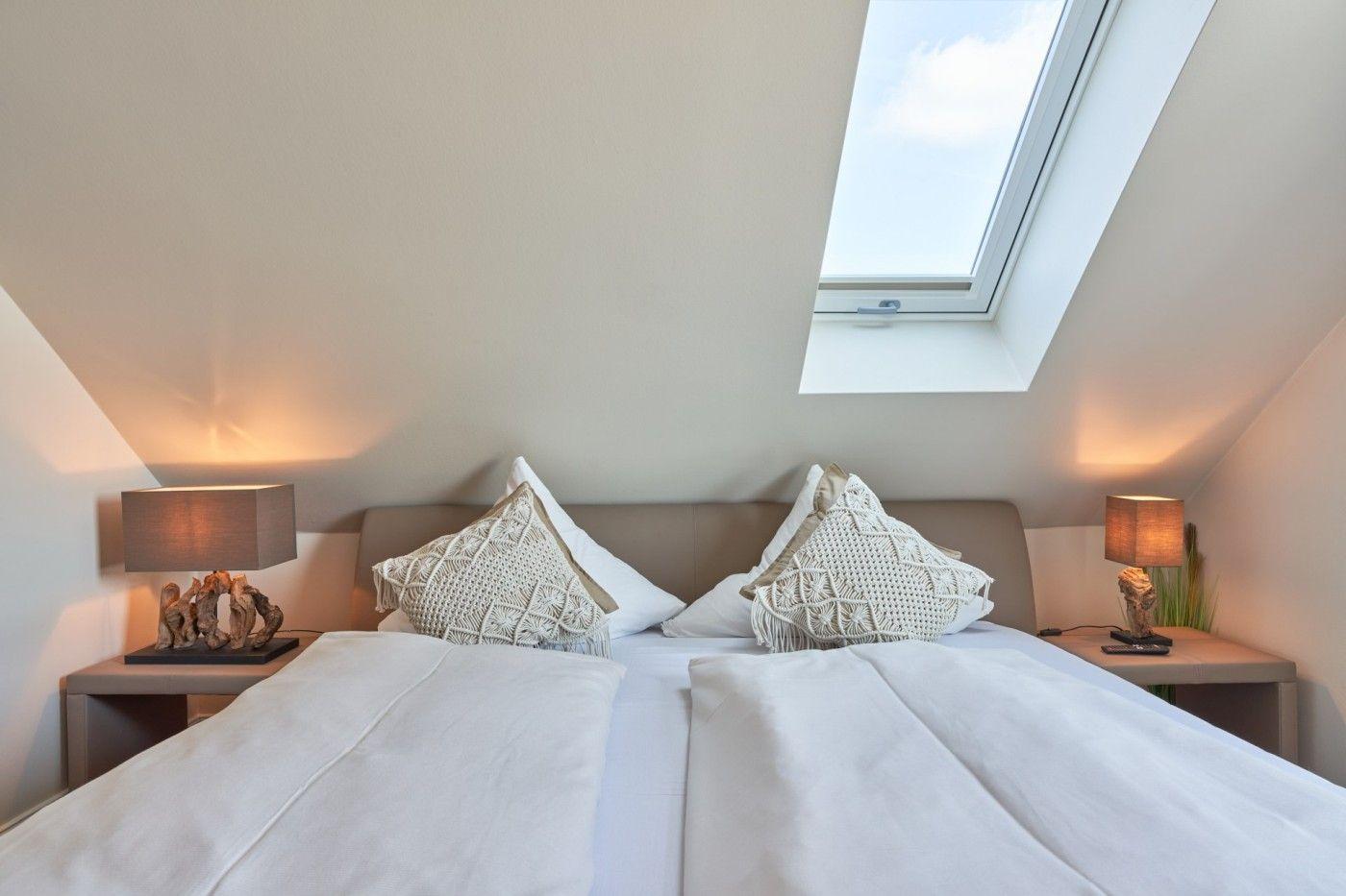 Schlafzimmer mit Dachschräge, Doppelschreibtisch und Dachfenster.