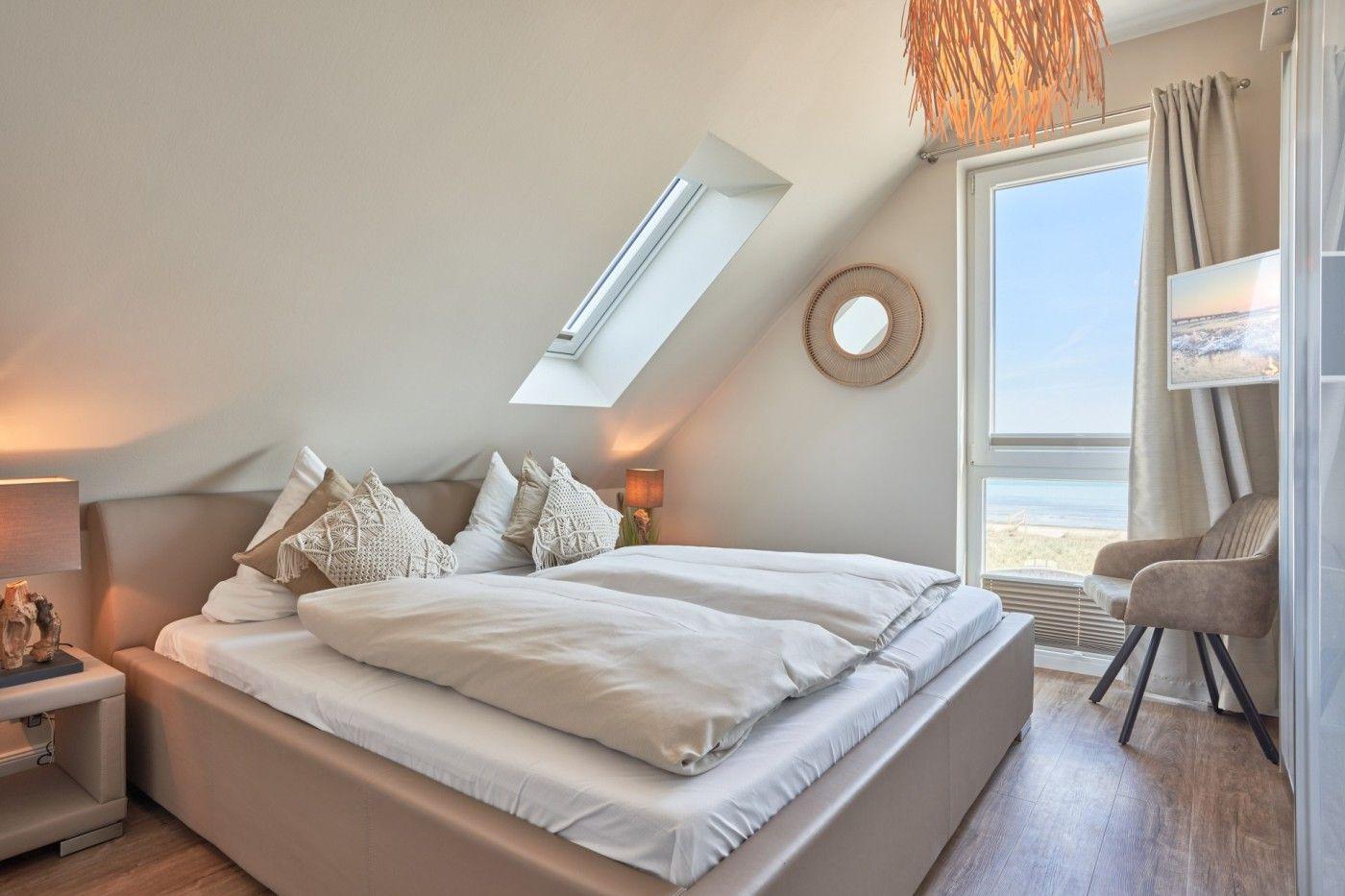 Schlafzimmer mit Dachschrägen, Dachfenster und großem Fenster mit Meerblick.