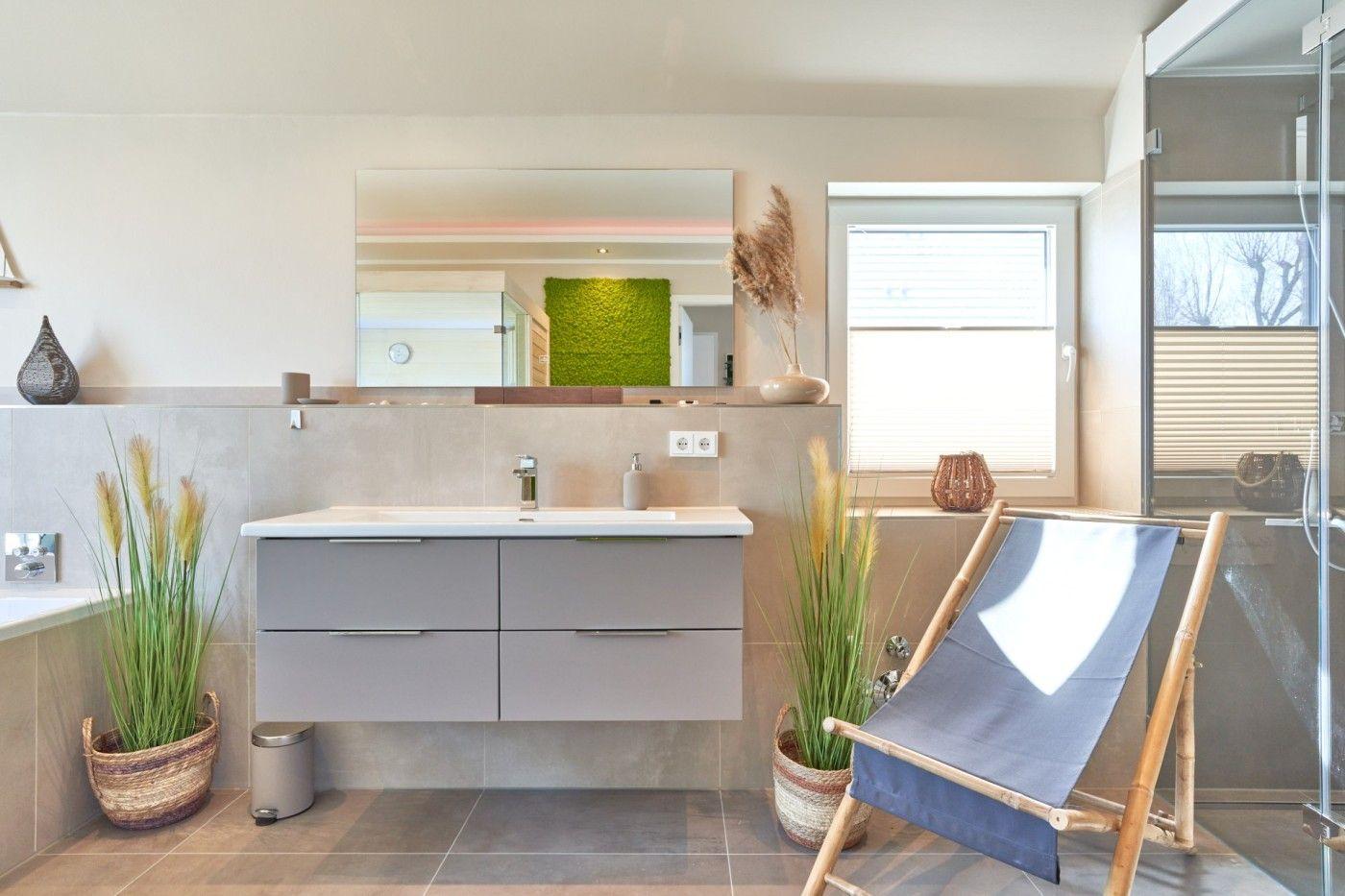 Badezimmer mit Waschtisch, Spiegel, Fenster und Liegestuhl.