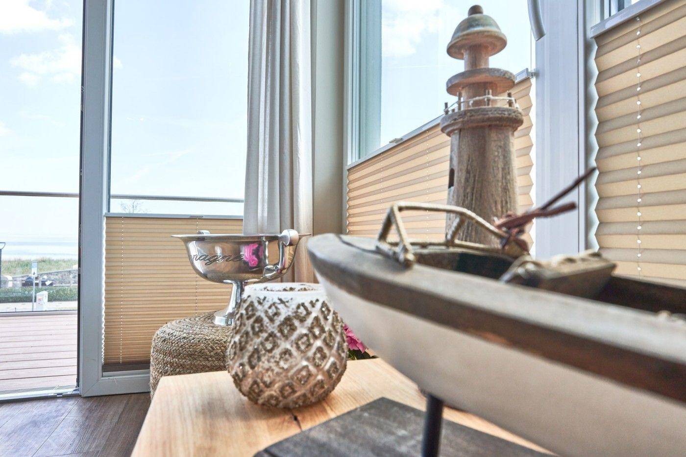 Tisch mit Segelboot und Laterne vor Fenster mit Meerblick
