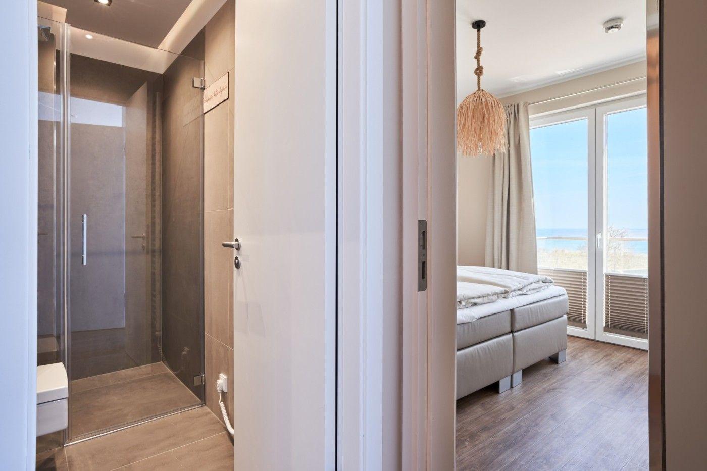 Schlafzimmer mit Blick aufs Meer und angrenzende Dusche.