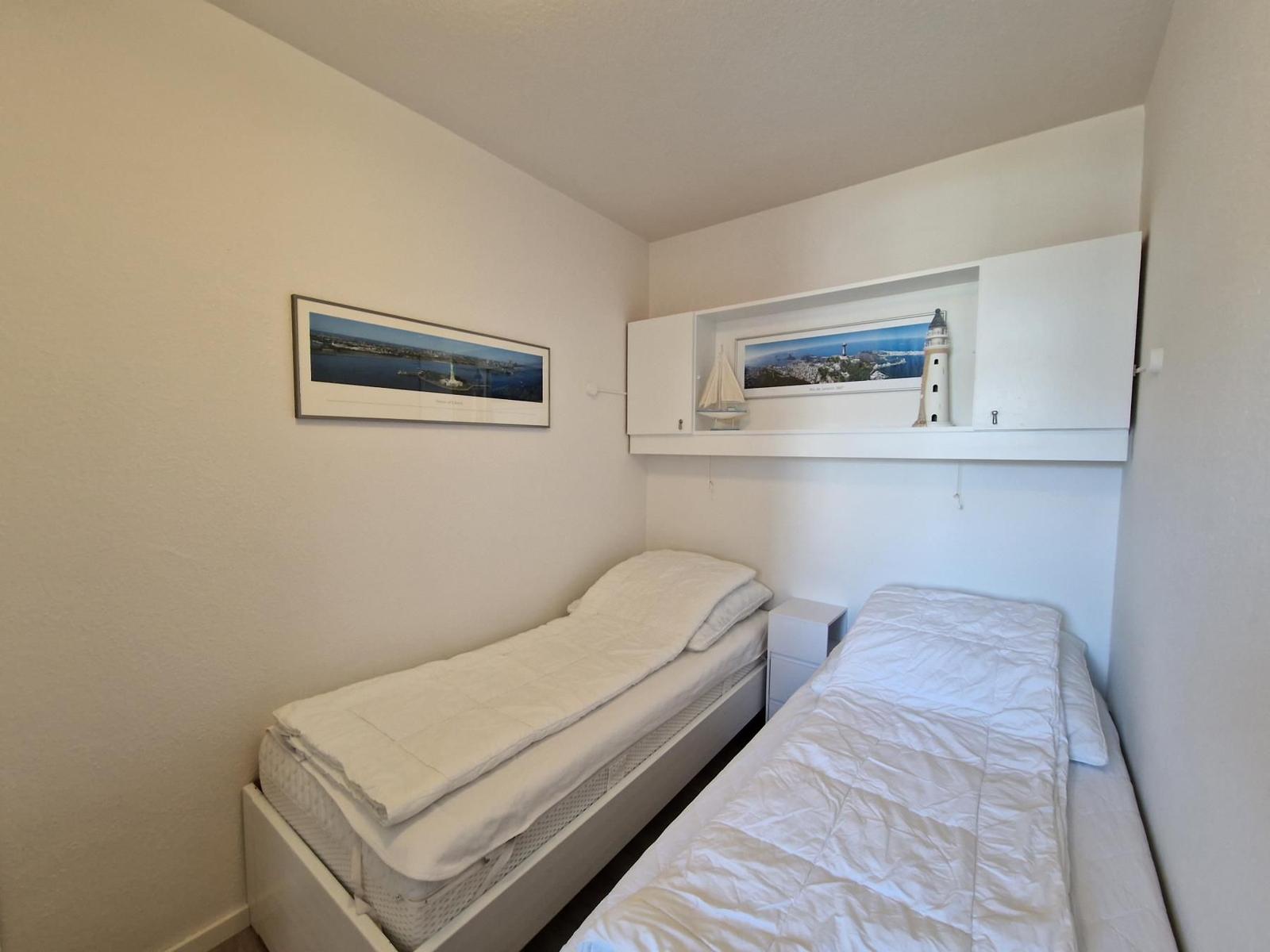 Zimmer mit zwei Betten, Wandbild und Schrank mit Dekoration.