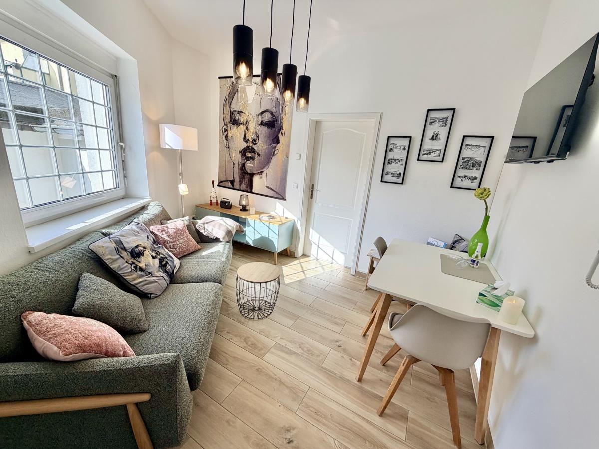 Wohnzimmer mit Sofa, Esstisch und Wandbild. Holzboden und Fenster mit Blick.