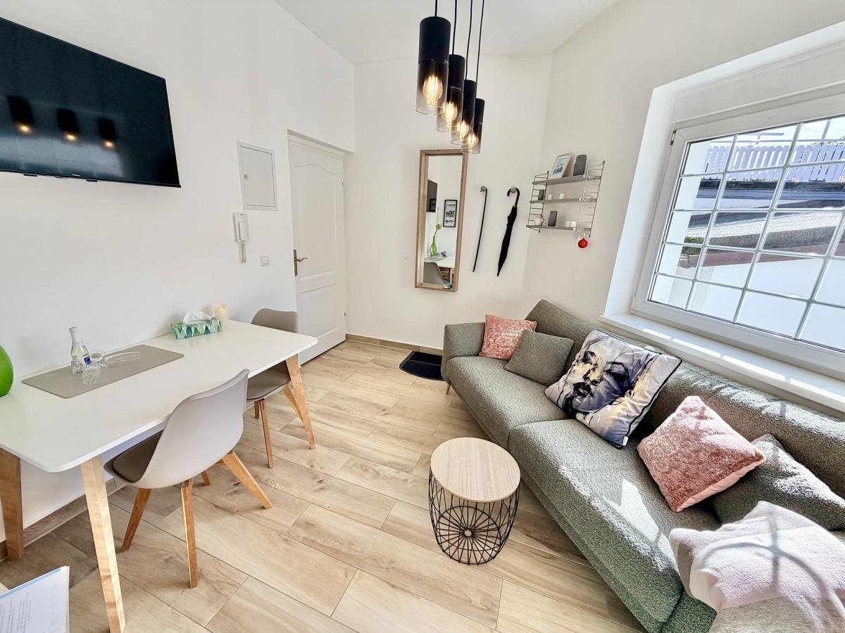 Wohnzimmer mit Sofa, Tisch und Fernseher an der Wand