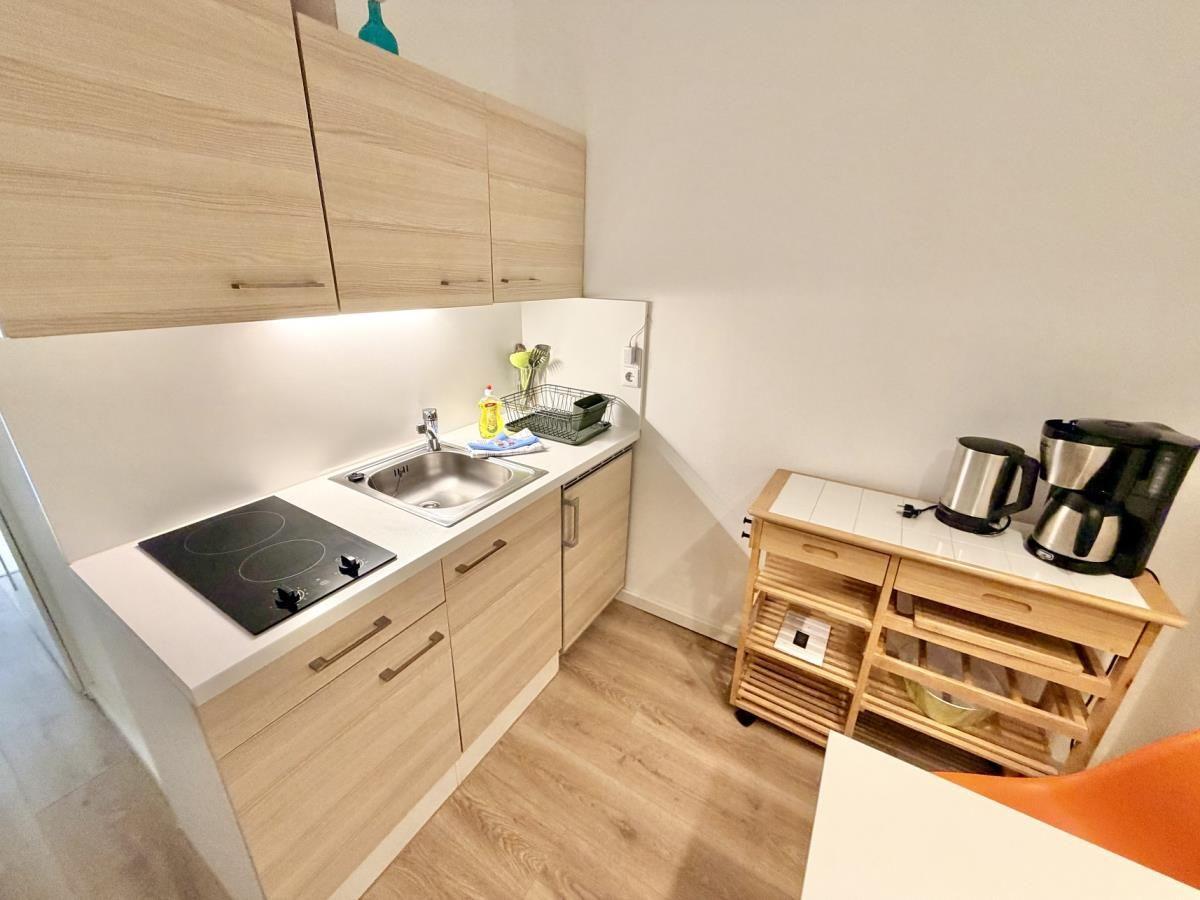 Küche mit Holzschränken, Induktionskochfeld, Spüle und Kaffeemaschine.