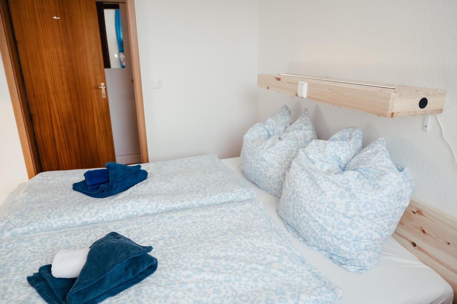 Schlafzimmer mit Bett, Kissen und Holzregal an der Wand.