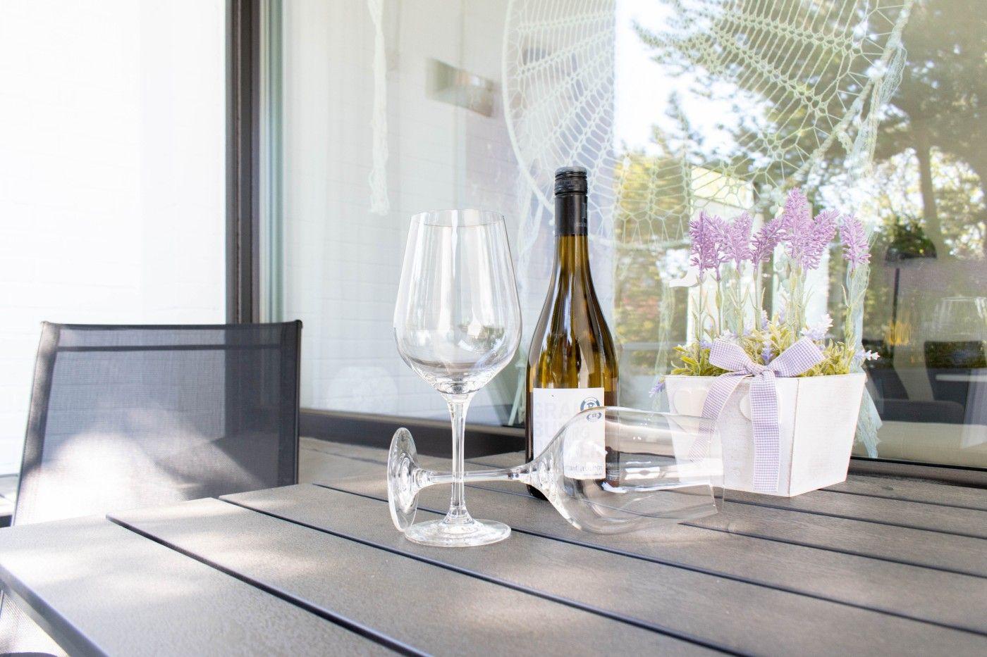 Auf der Terrasse steht ein Tisch mit Weinflasche, zwei Gläsern und einer Lavendeldekoration.