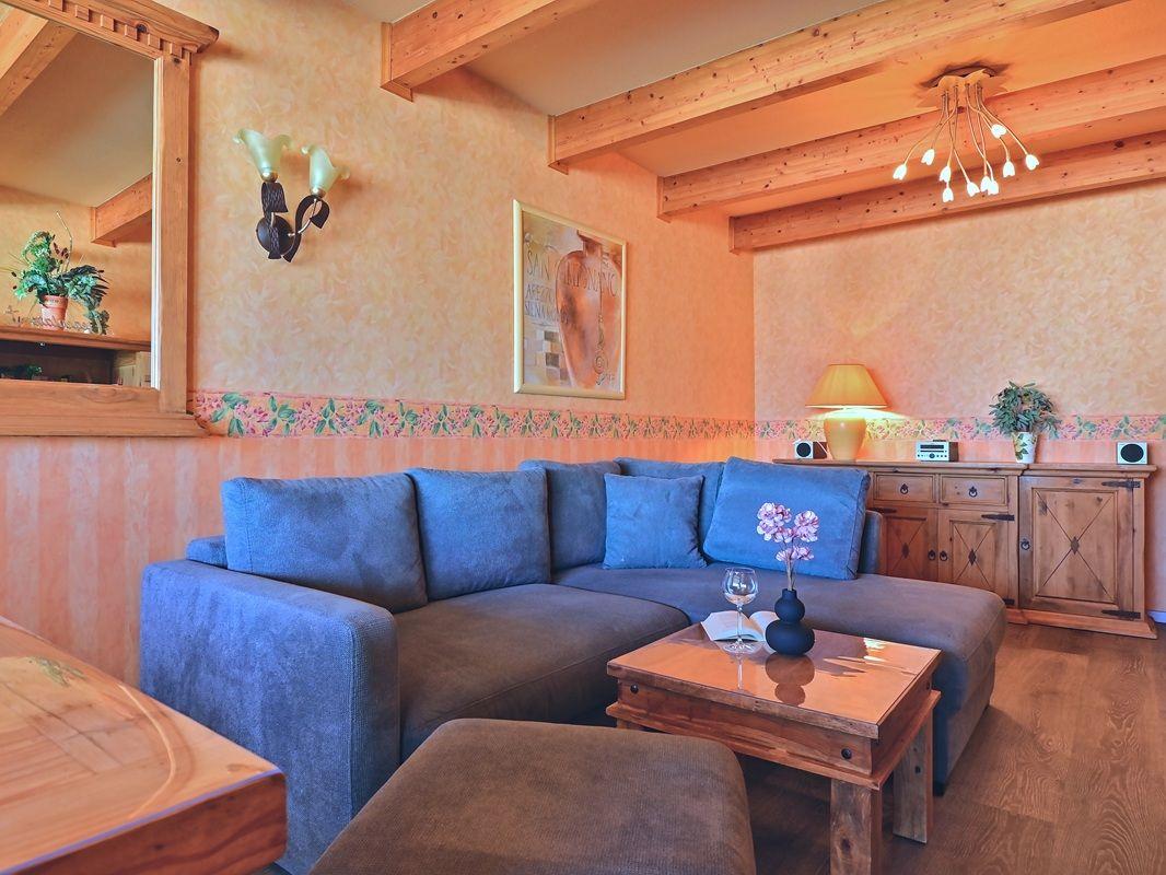 Ein Wohnzimmer mit blauem Sofa, Holzmöbeln und einer Deckenleuchte.