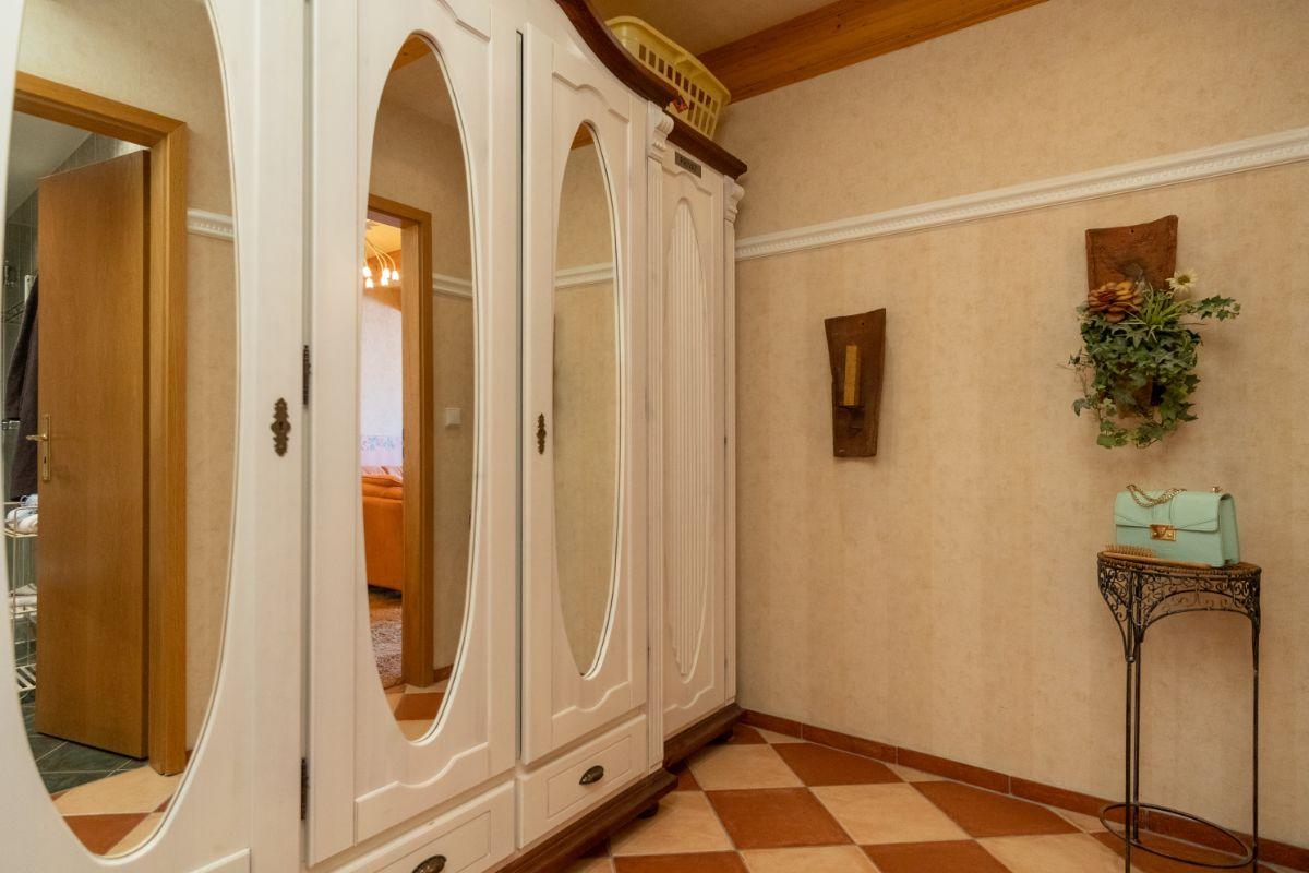 Ein Flur mit einem weißen Schrank mit Spiegeltüren, einer Wanddekoration und einem Boden mit Schachbrettmuster.