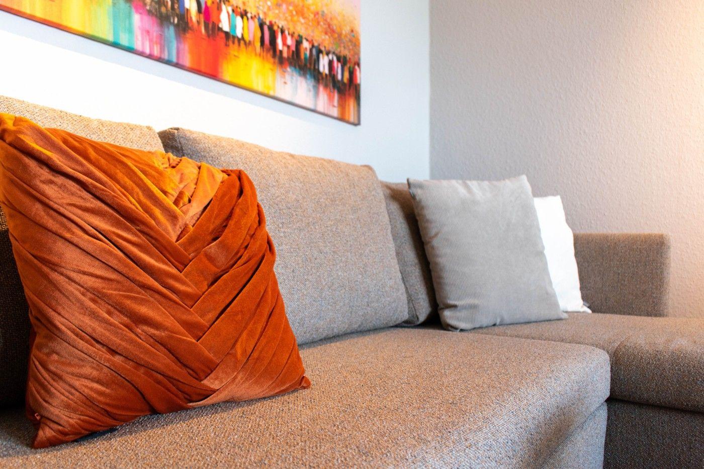 Ein Sofa mit Kissen und Wandbild